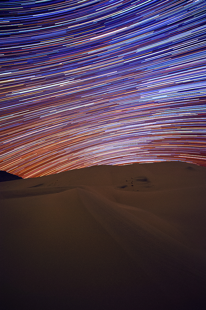 Star Trails from multiple exposures make colorful light lines arcing through the night sky.