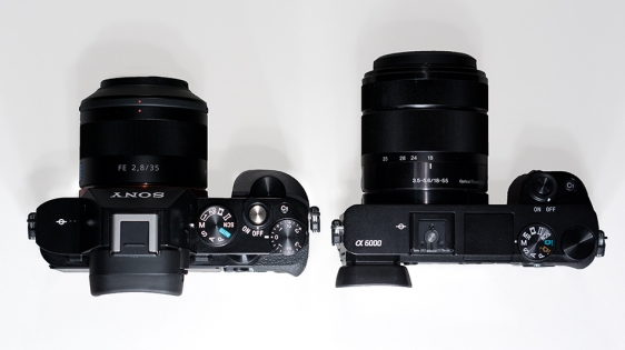 A7R (left) and the A6000. On the slimmer A6000, note the left justified viewfinder, pop up flash, no compensation dial, no front dial, no quick access to memory settings 1&2, no hot shoe cover.